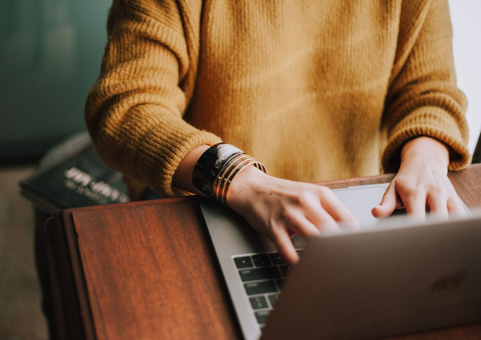 Image shows someone sitting at a desk typing on a laptop in front of them