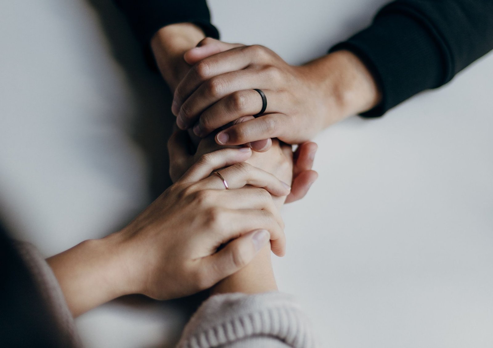 Image shows two people providing emotional support and comforting each other by holding hands across table