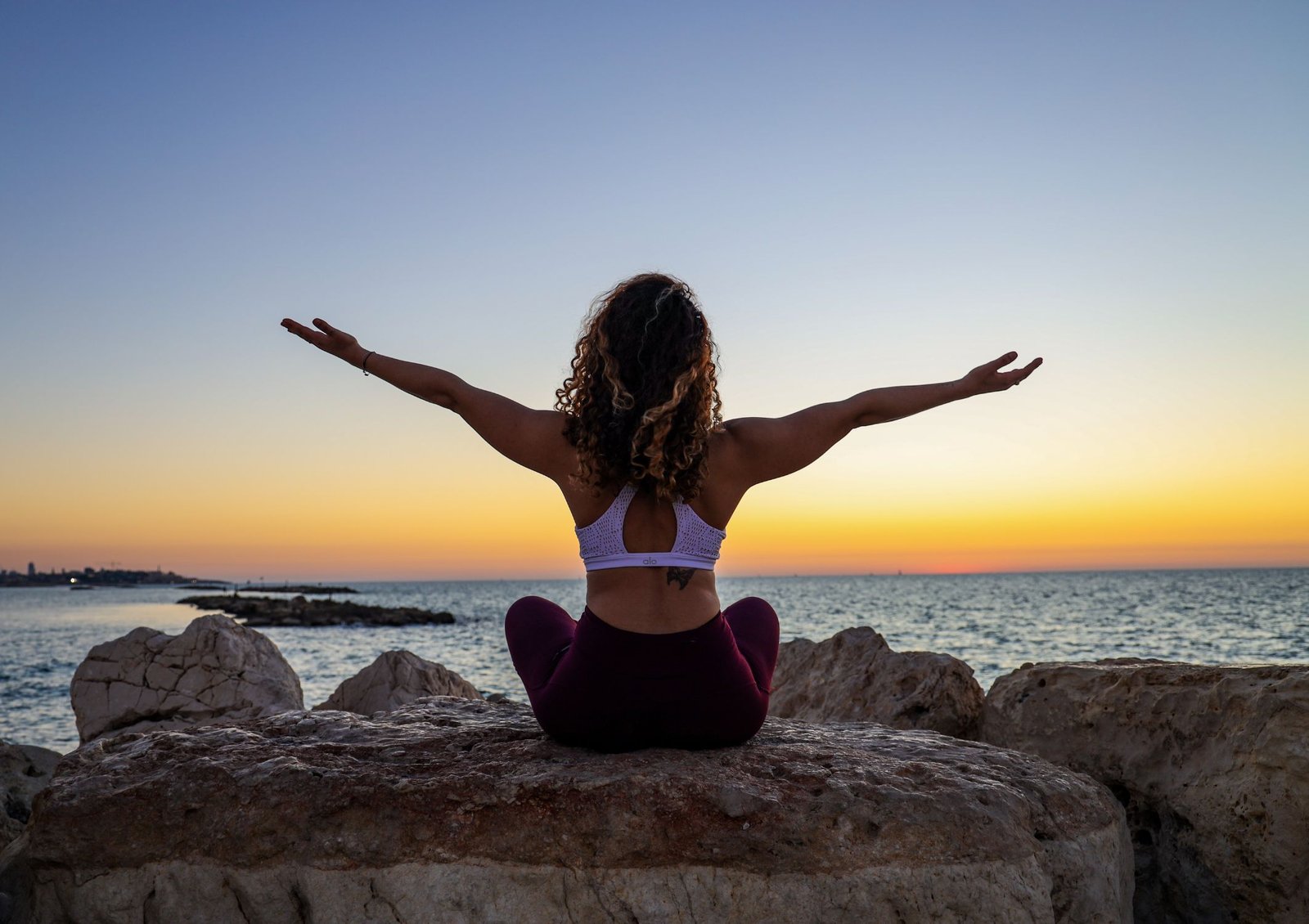 Person standing amid a beautiful sunrise with arms open wide embracing life and feeling content and happy while mindfully taking it all in.