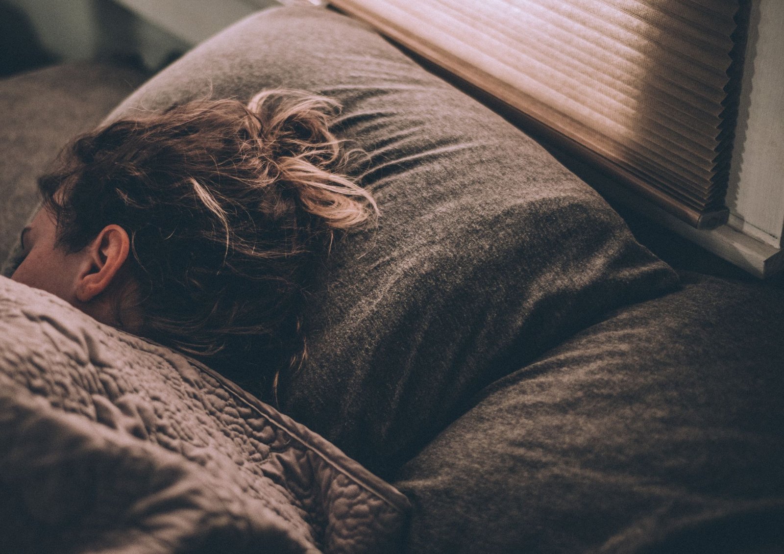 Image shows someone in bed, in a deep restorative sleep, benefiting their mental health and wellbeing